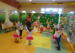 Dzieci tańczą w kole, w rękach trzymają chusteczki, które unoszą w górę.